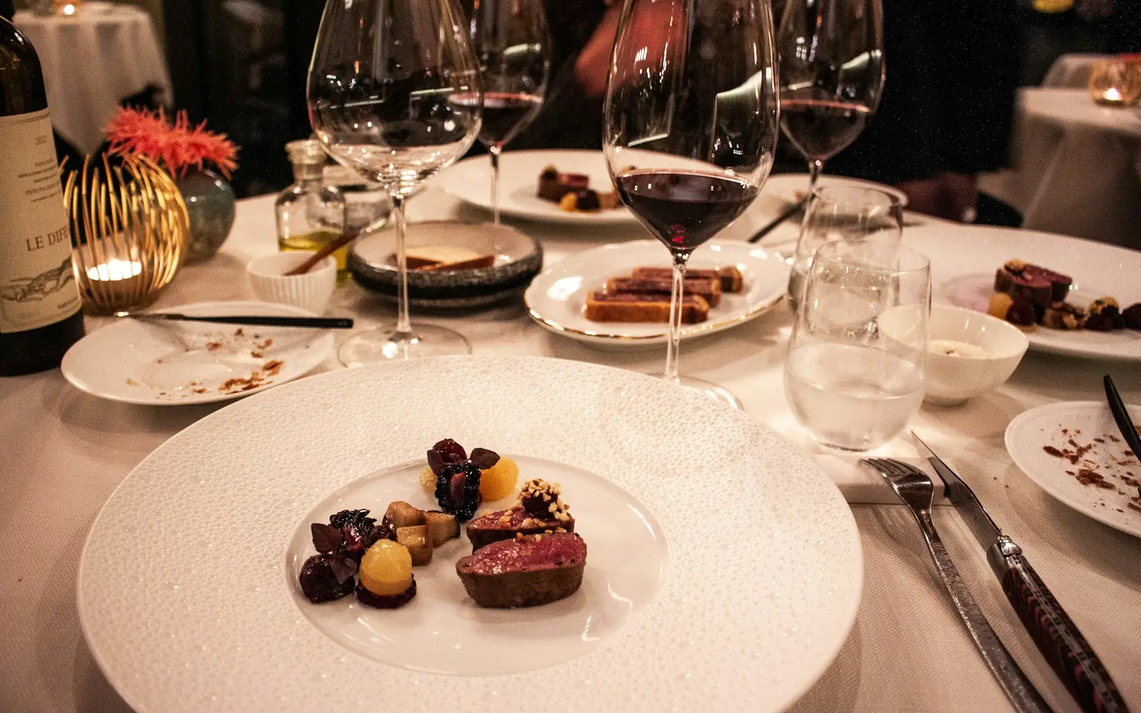 Mesa posta com copos de vinho e pratos de comida.
